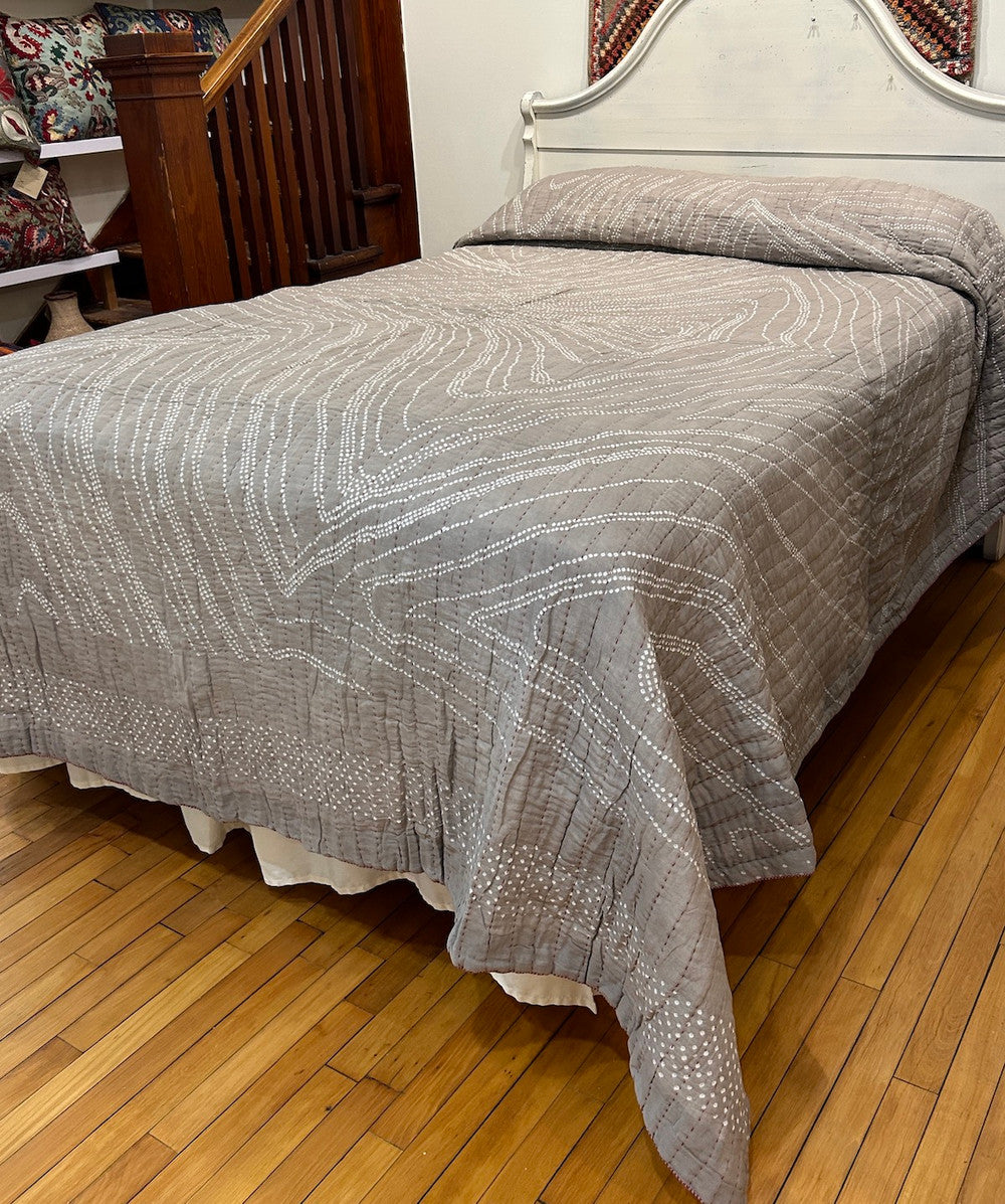 view 2 One-of-a-kind bandhani dyed and hand stitched cotton quilt by Jabbar and Abdullah Khatri, internationally acclaimed folk artists, Gujarat, India. This quilt is a work of art! The design is a organic flowing design of fine tie dyed pattern and the whole quilt has rows of red hand stitching. The rows 1 inch apart. Colors: taupe tan with white dots. The quilt has a thin cotton batting. This is a hand dyed fabric, irregularities are to be expected. The backing in handwoven cotton cloth.