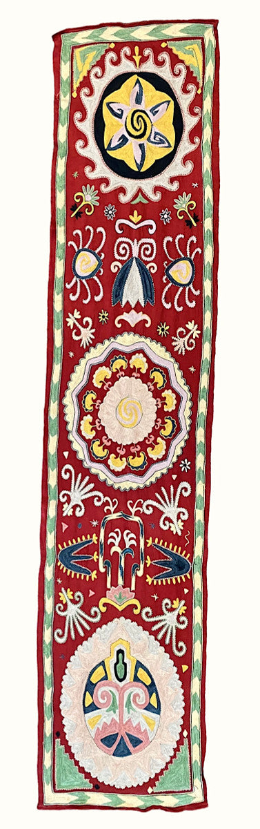 Hand Embroidered Silk Table Wall Hanging Uzbekistan Embroidery colors: chalky leaf green, pinkish cream, pale bluish cream, chalky pale pink, pale violet cream, pale yellow, Prussian blue, gold, and black that sit atop a silk ground cloth of deep red