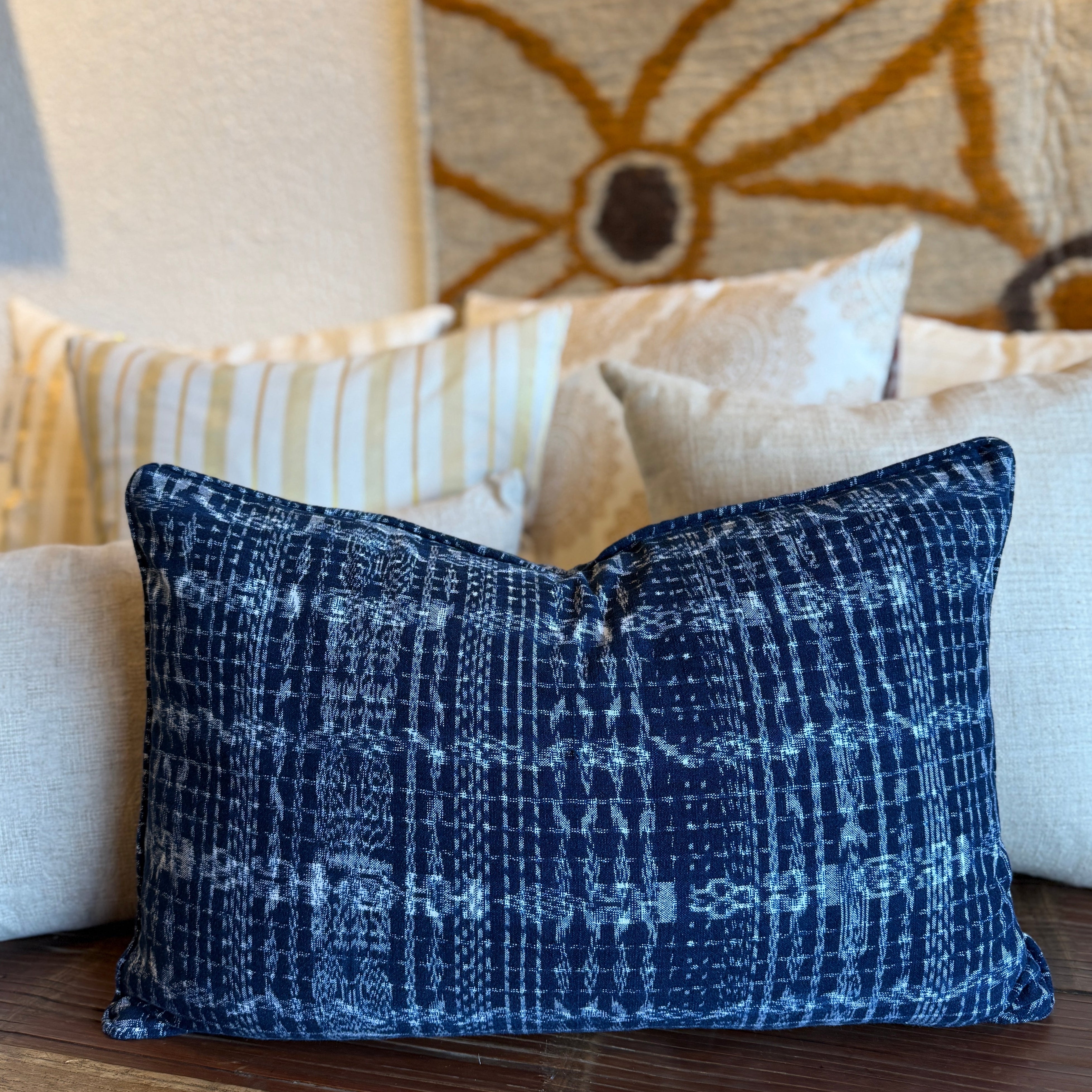 Blue patterned pillow on a wooden surface with a floral rug in the background