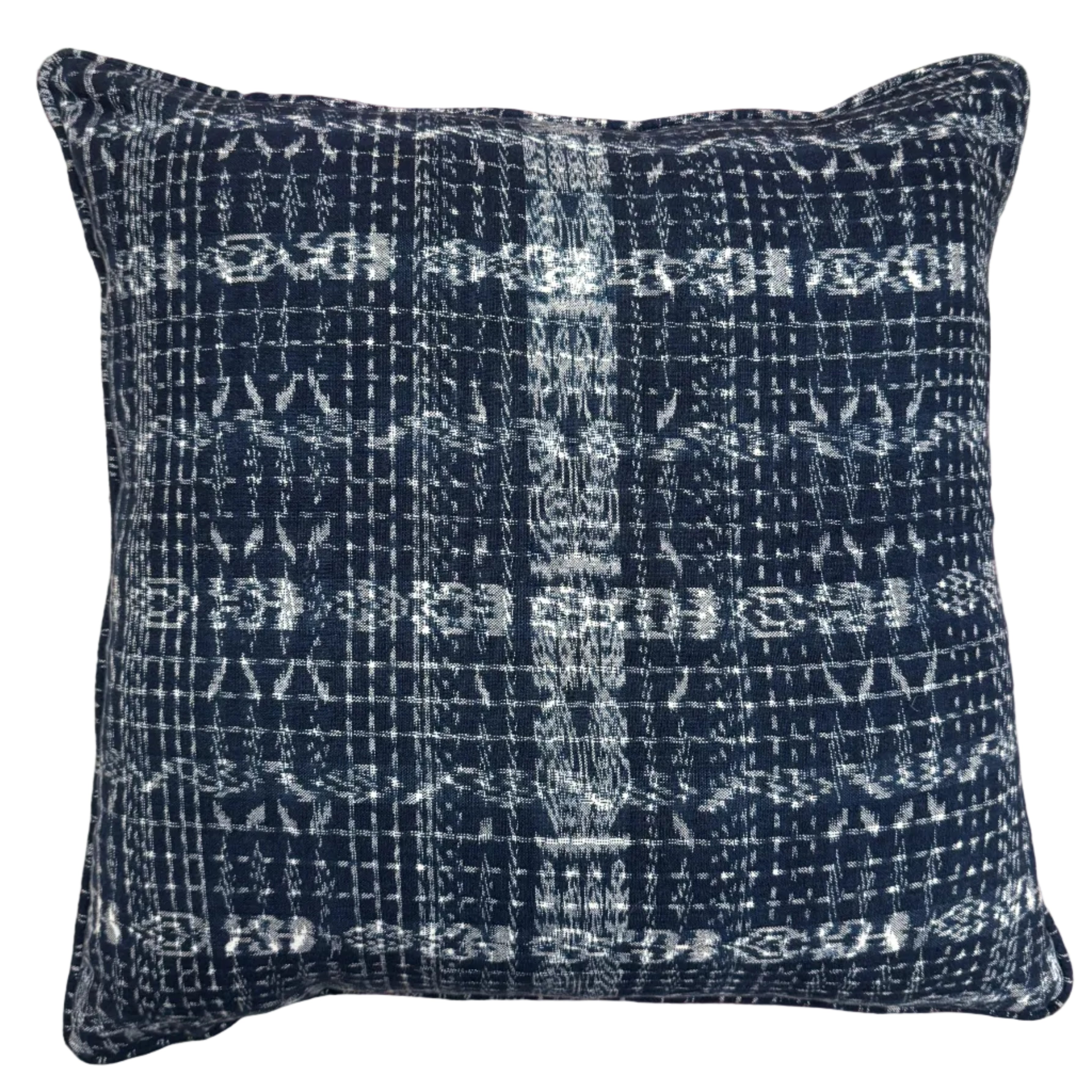 Blue textured pillow on a couch with a floral-patterned wall in the background