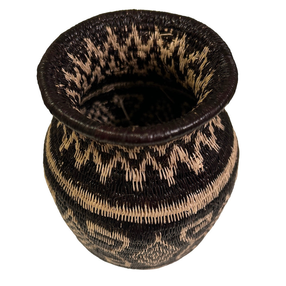 top view This small fine basket is made from natural palm fronds cut into fine strips. The sturdy basket is woven with a complex technique and with a fine tight pattern. The Wounaan women are considered the finest basket makers in the world. Through basketry they help preserve their culture and in so doing they respect the earth with sustainable harvesting practices. Colors: black, and wheat. 