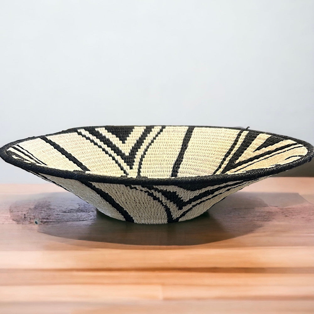 Handwoven Natural Fiber Basket Eswatini Handwoven natural fiber basket made with natural sisal from sustainably harvested sources. This is from a small artisan organization that has been working in Eswatini (Swaziland) since 1985. Very sturdy. Beautiful on the table or on the wall. Colors: cream and black