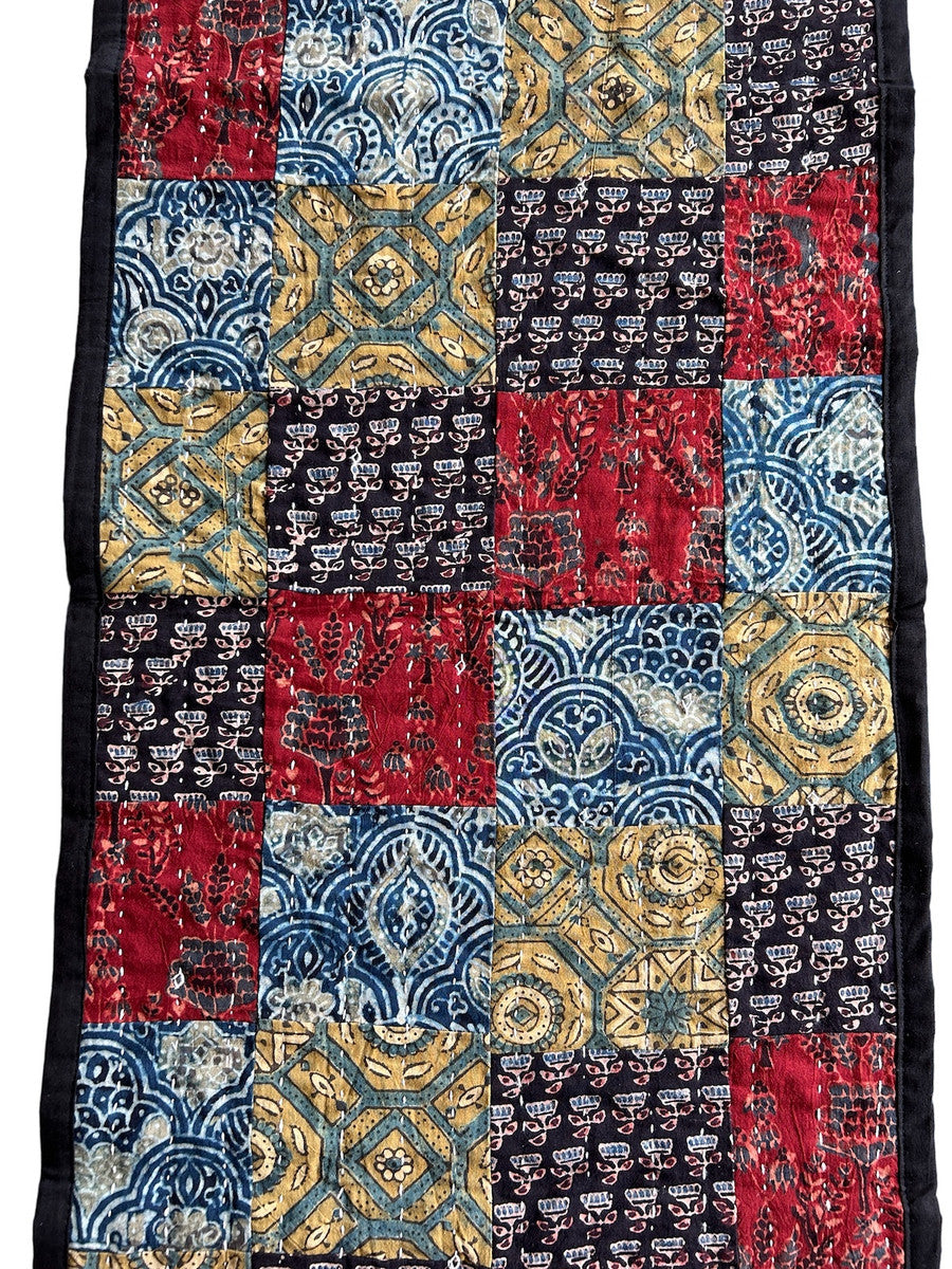 detail Handmade table runner of block printed fabrics. The fabrics are made with several wooden blocks using the traditional Ajarakh natural dye technique. The fabric is then sewn into a patchwork of various colors and patterns.  Beautiful combination of colors: indigo blue, brick red, black, greenish gold, pale blue grey and more. 1" solid black edging around. The back is solid black with white stitching. This can be reversible 

