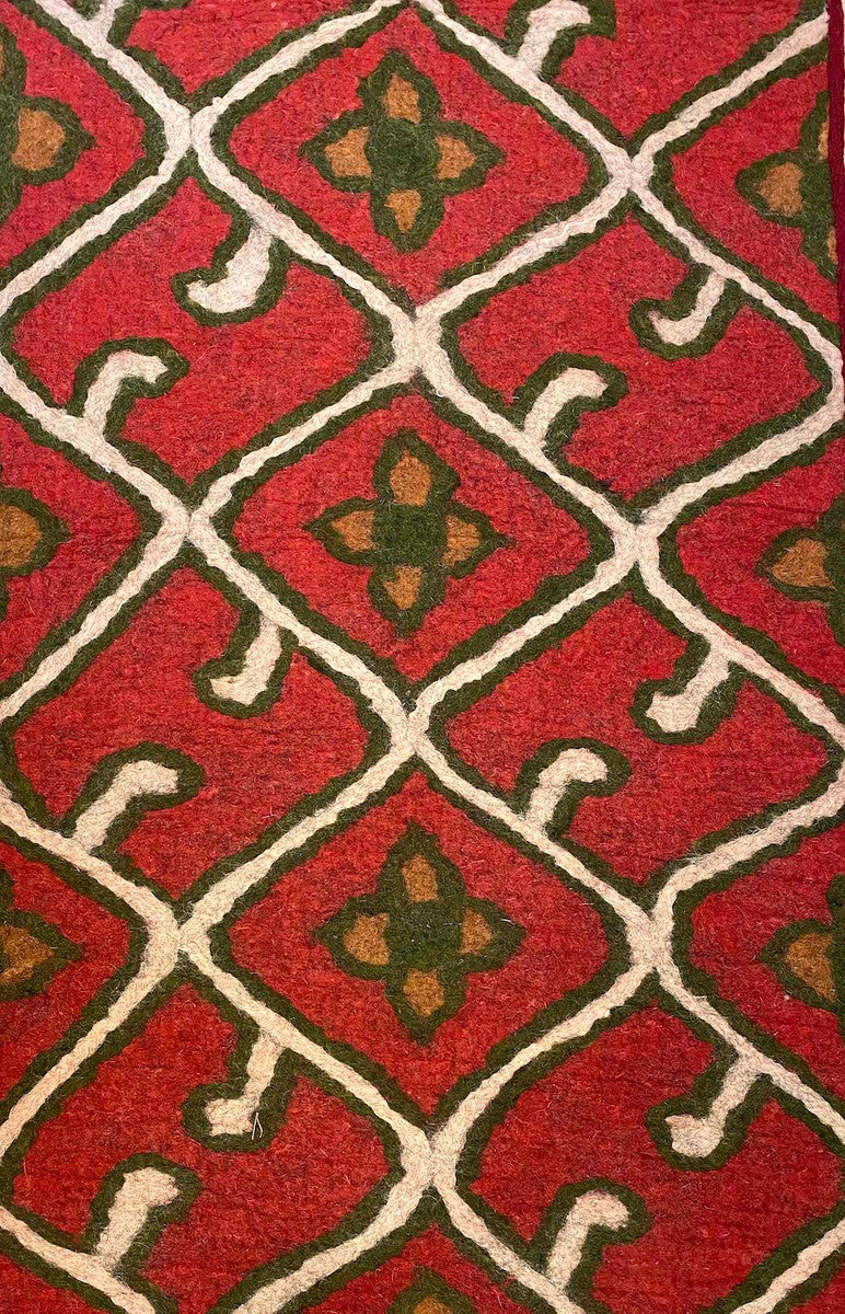The floral lattice pattern colors are natural white, deep olive and tobacco on a red field There is a dark red colored woven border sewn around the whole rug
