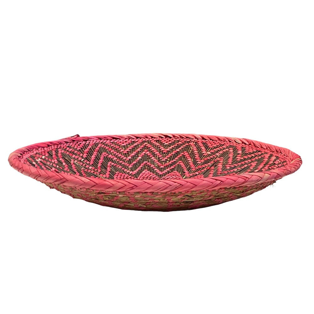 side view Handmade Natural Twig and Palm Leaf Basket Zimbabwe top view 216" wide x 5" tall Brown twigs woven with palm leaves dyed in shades of bright pink.